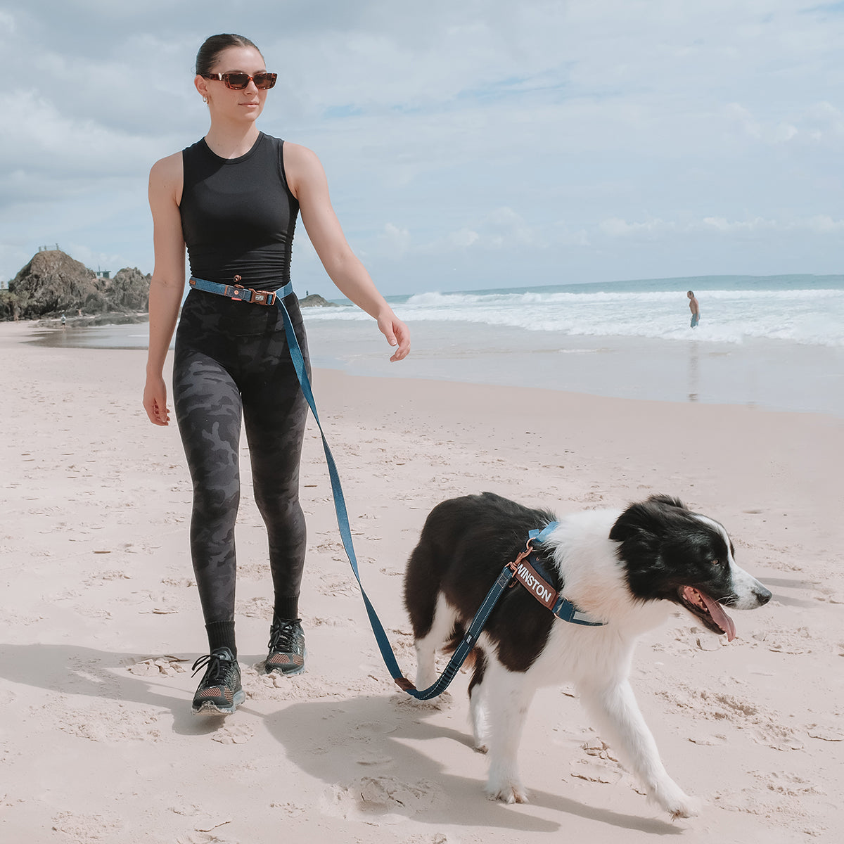 Woman walking dog on the beach using blue EzyDog Road Runner Leash in hands-free waist mode